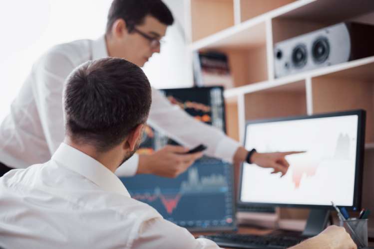 Analyzing data. Close-up of young business team working together in creative office while young woman pointing on the data presented in the chart with pen